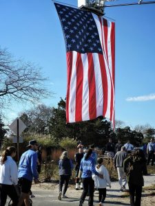 american-flag-hangs-above-a-crowd-outdoors-gathering-of-people-etjmkkwgtq
